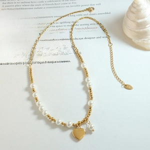 Elegant gold heart pendant necklace with white pearls and K18 hallmark on a magazine