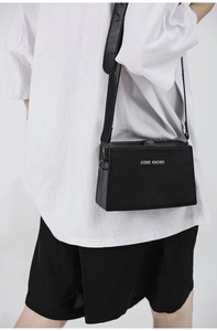 Close-up of matte black box bag featuring silver Cone Knows logo and structured texture