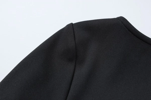 Close-up of black bodycon dress showing textured knit fabric and stitching details