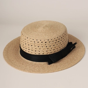Detailed texture of hand-woven raffia flat-top boater hat with black grosgrain ribbon bow