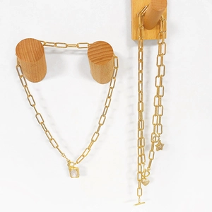 Détail du collier à grosse chaîne dorée avec fermoir OT et breloques étoile et cœur