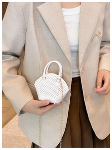 Close-up of white mini shell handbag with woven texture leather and gold chain strap