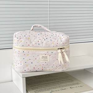 Detailed view of quilted pink polka dot makeup bag with bow print and ribbon zippers