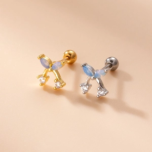Close-up of gold and silver bow stud earrings with opals and sparkling zircons