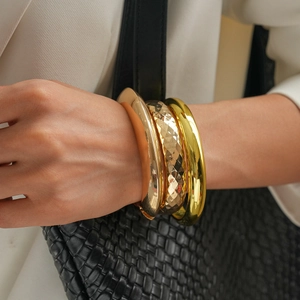 Close-up of a three-piece geometric metal cuff bracelet set in gold and rose gold