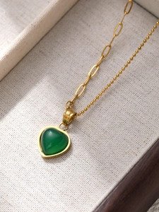 Dettaglio della collana d'oro con ciondolo a cuore verde e catena mista in scatola regalo