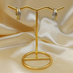 Macro detail of mixed-tone gold and silver textured hoop earrings on a display stand