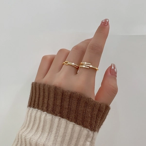 Close-up of golden geometric cross ring with sparkling zircons worn by a model