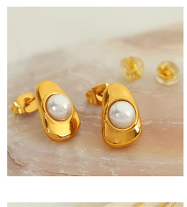Detailed macro shot of irregular golden oval earrings with white pearl inlay on stone