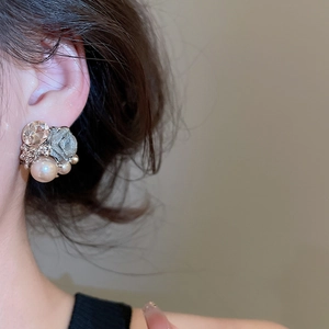Detailed close-up of a floral cluster earring with pearls and sparkling rhinestones