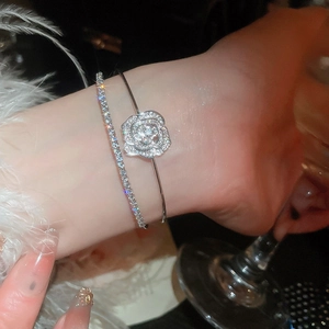 Detail shot of double-layer silver flower bracelet with zircon stones on female wrist