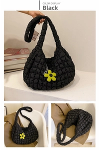 Detail of black quilted cloud tote bag featuring a yellow sunflower charm accessory