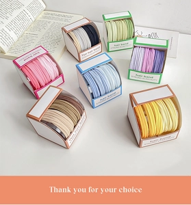 Close-up of colorful thick hair bands in minimalist box packaging with book decor