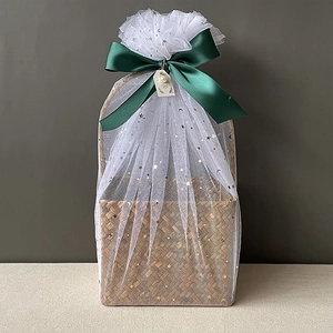 Detail of woven seagrass basket with star tulle wrap and green satin ribbon bow