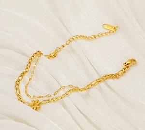 Detail of 18K gold layered daisy bracelet on white silk with Figaro and curb chain links