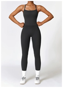 Detail of high-waist black yoga leggings and cross-strap sports bra on a fit model