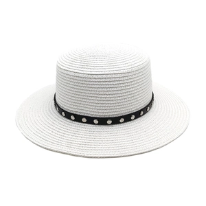 Détail d'un chapeau de paille blanc avec ruban en cuir noir orné de clous métalliques
