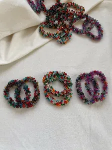 Detail shot of colorful faceted crystal beads hair ties on a soft linen background