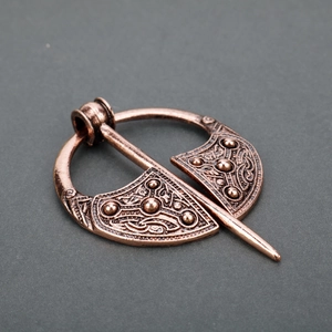 Detail of vintage Viking metal brooch with intricate bronze embossed patterns and pin