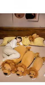 Three sizes of soft lion plush pillows shown in a cozy bedroom setting for kids