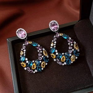 Macro detail of vintage water-drop earrings with colorful gemstones and black metal base