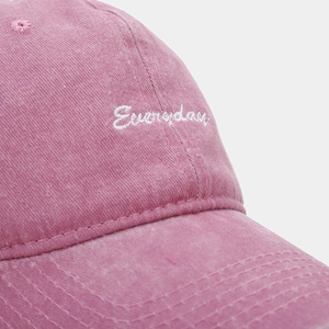 Detailed macro view of white 'Everyday' embroidery on washed cotton pink baseball cap