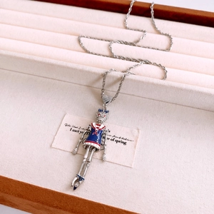 Close-up of vintage skeleton pendant with blue sailor dress on beige jewelry tray
