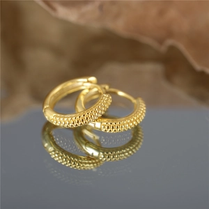 Classic gold S925 sterling silver hoop earrings with a textured bead surface on a mirror