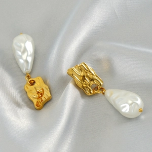 Detailed close-up of Baroque pearl drop earrings with textured gold metal on silk background
