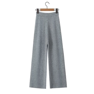 Detail of grey knitted wide-leg trousers with vertical ribbed texture on wooden hanger