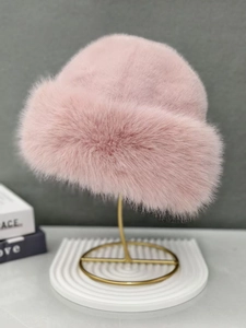Detail of soft pink faux fur bucket hat displayed on a premium gold metal stand