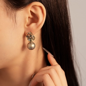 Vintage gold earrings with grey pearls and rhinestones shown on model in close-up view
