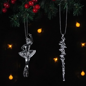 Clear ballerina and icicle Christmas ornaments hanging on festive pine branches