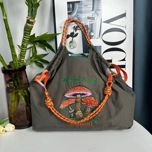 Olive green nylon tote bag with mushroom embroidery and colorful woven rope handles