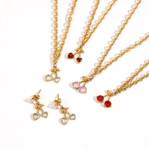 Dettaglio collana e orecchini a ciliegia in oro con zirconi rossi a forma di cuore