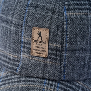 Macro detail of thick wool plaid baseball cap with blue grid and leather patch