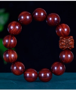 Detailed macro view of polished sandalwood prayer beads with a carved PiXiu charm