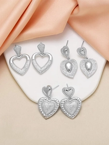 Detailed view of silver heart earrings with pavé cubic zirconia on pink silk fabric