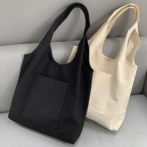 Detail view of black and beige canvas tote bags with front pockets on a sofa