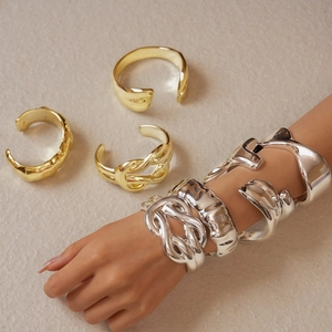 Detail of twisted and irregular geometric metal cuff bracelets in gold and silver finish