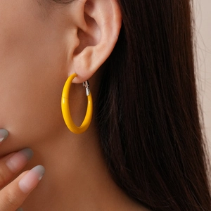 Close-up of a matte bright yellow geometric hoop earring worn by a model