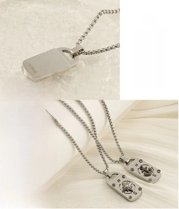 Détail de pendentifs en acier inoxydable avec gravures de boussole et ancre sur chaîne