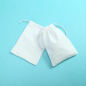 Two white cotton drawstring pouches for jewelry storage on a light blue background