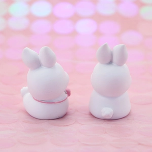 Rear view of two cute white rabbit figurines with pink bows on a dreamy background