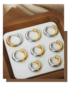 Detail view of two-tone gold and silver titanium steel hoop earrings on a velvet tray