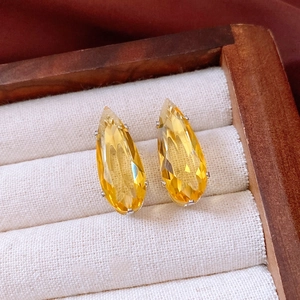 Detailed close-up of yellow teardrop zircon earrings in a cream velvet jewelry box