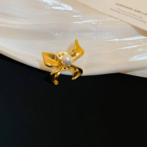 Detail of gold ribbon brooch with central pearl and secure butterfly clasp closure