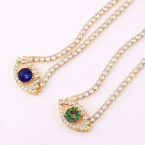 Detail of gold evil eye pendants with blue and green stones on crystal tennis chains