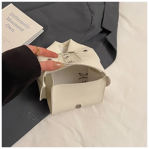 Close-up of cream mini bag shaped like a jacket with magnetic clasp and button detail