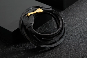Dettaglio bracciale multistrato in pelle intrecciata nera con chiusura a amo dorata